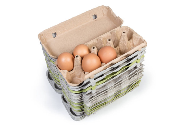 Farklı açık boş yumurta kartonları yığını geri dönüşümlü kağıt hamuru bir üst paket beyaz bir arka plan üzerinde birkaç kahverengi tavuk yumurtası ile yapılmış - Fotoğraf, Görsel