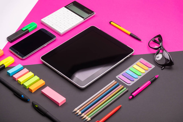 Picture of modern artspace with tablet, glasses, stationery and smartphone on pink and black background. Flat lay style - Foto, Imagen