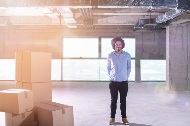 ritratto di giovane imprenditore in cantiere controllando documenti e flussi di lavoro aziendali con scatole di cartone intorno a sé in un nuovo ufficio startup - Foto, immagini
