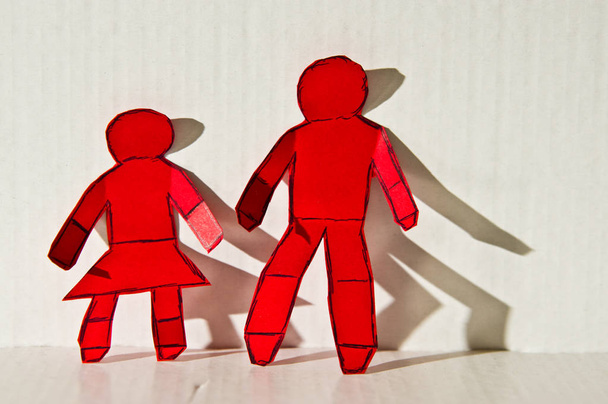 Абстрактне зображення червоних паперових фігур чоловіка і жінки, що стоять разом
. - Фото, зображення
