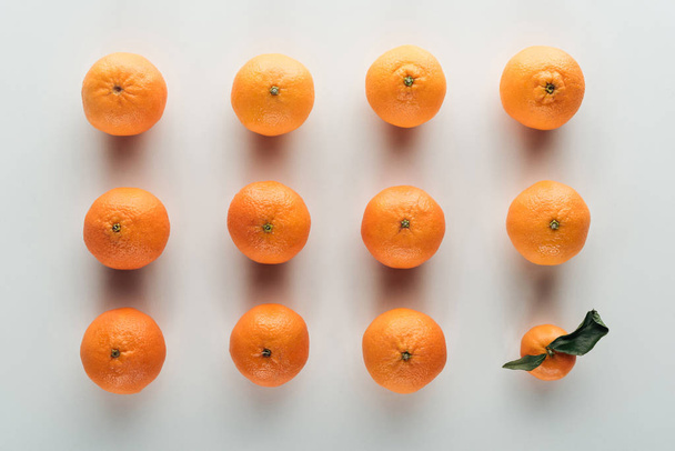 flat lay with bright ripe orange tangerines and one with green leaves - Photo, Image