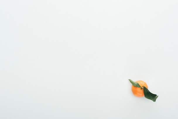 bright ripe orange tangerine with green leaves on white background with copy space - Fotó, kép