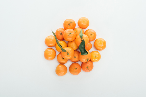top view of bright ripe orange tangerines with green leaves stacked in pile on white background - Photo, Image