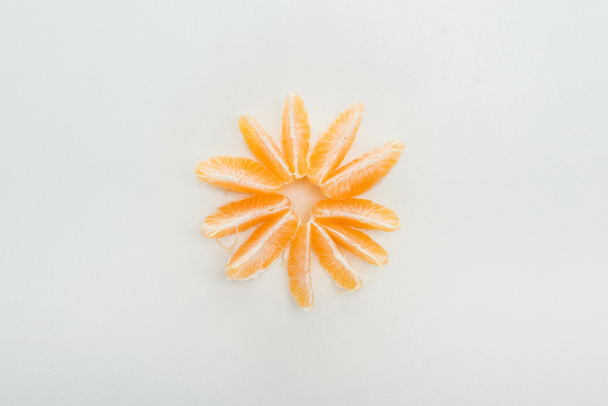 tendido plano con rodajas de mandarina peladas dispuestas en círculo sobre fondo blanco
 - Foto, Imagen
