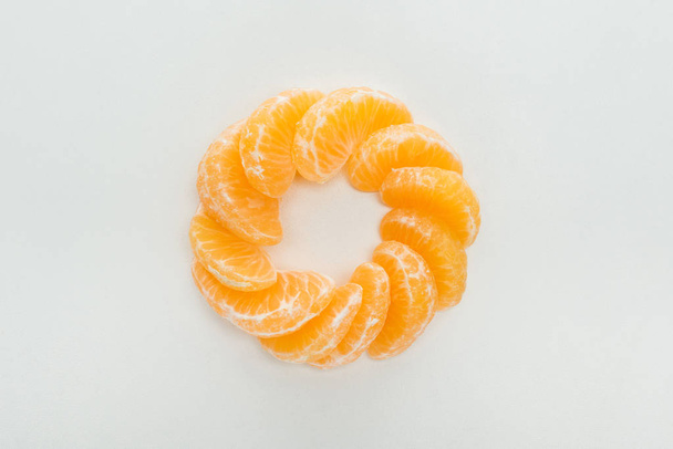 flat lay with peeled tangerine slices arranged in circle on white background - Foto, afbeelding
