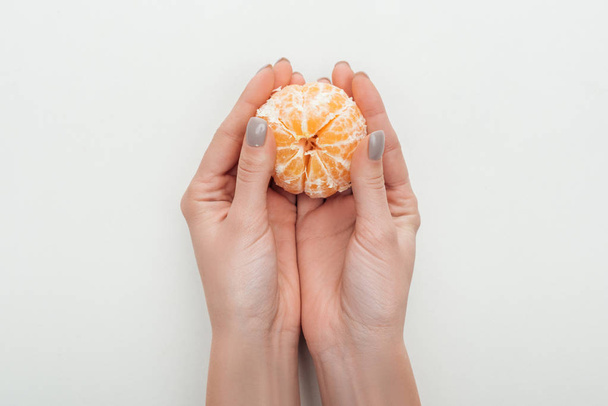 Teilansicht der Frau mit geschälter ganzer Mandarine auf weißem Hintergrund - Foto, Bild