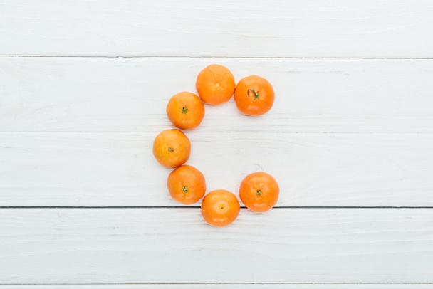 top view of letter c made of fresh tangerines on wooden white background - Photo, Image