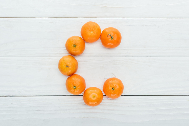 top view of letter C made of fresh tangerines on wooden white background - Фото, зображення