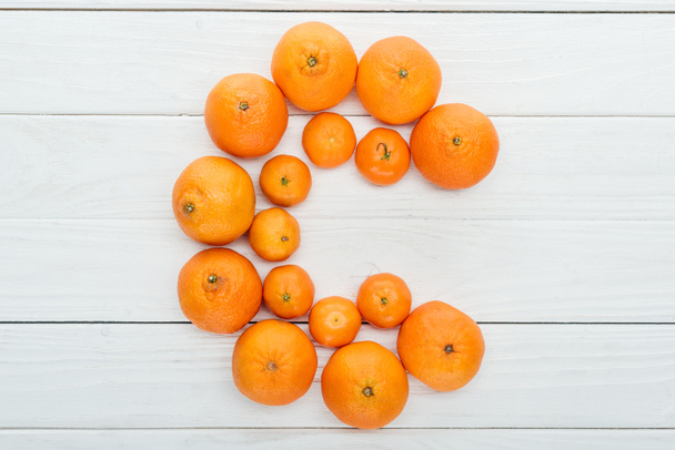 pohled shora písmene C vyrobený z čerstvé mandarinky na dřevěný bílý povrch - Fotografie, Obrázek