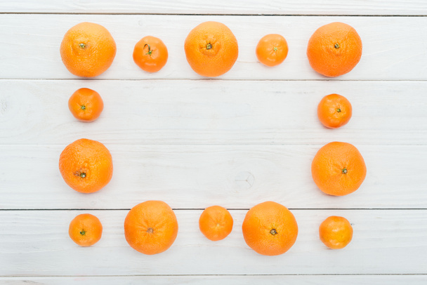 top view of square frame made of ripe orange tangerines on wooden white surface - Foto, Imagen