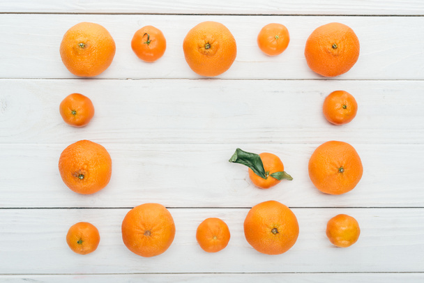 top view of square frame made of ripe orange tangerines on wooden white background - Foto, Imagen