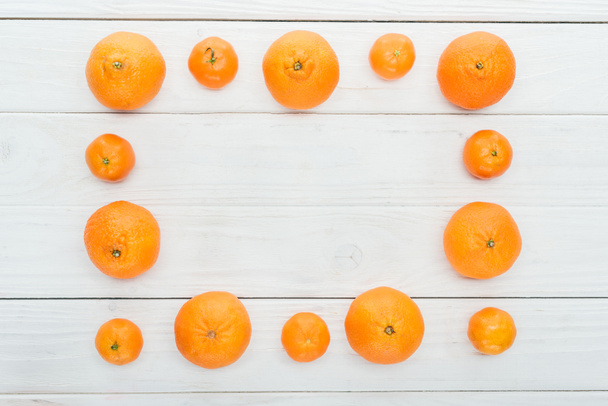 top view of square frame made of ripe orange tangerines on wooden white surface - Zdjęcie, obraz