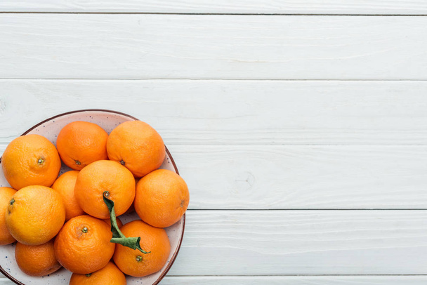 vista superior de mandarinas naranjas maduras en placa sobre fondo blanco de madera
 - Foto, Imagen