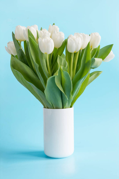 Bouquet of white tulip in vase on pastel blue. Spring concept. - Foto, imagen