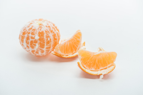 Mandarinenscheiben mit Schale und ganzen Früchten auf weißem Hintergrund - Foto, Bild