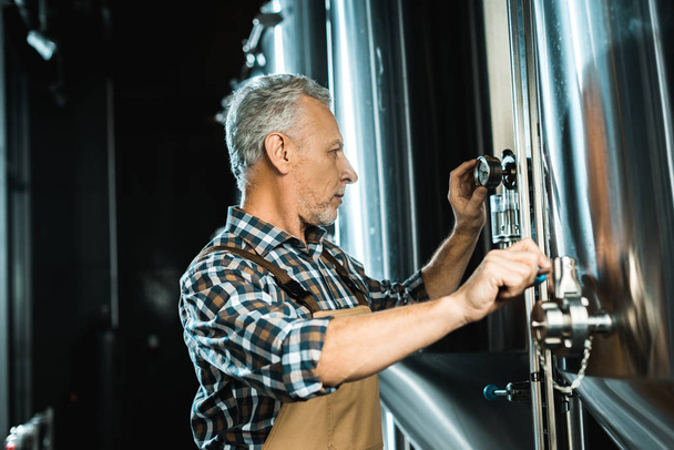 professionelle Senior-Brauer arbeiten mit Brauereiausrüstung - Foto, Bild