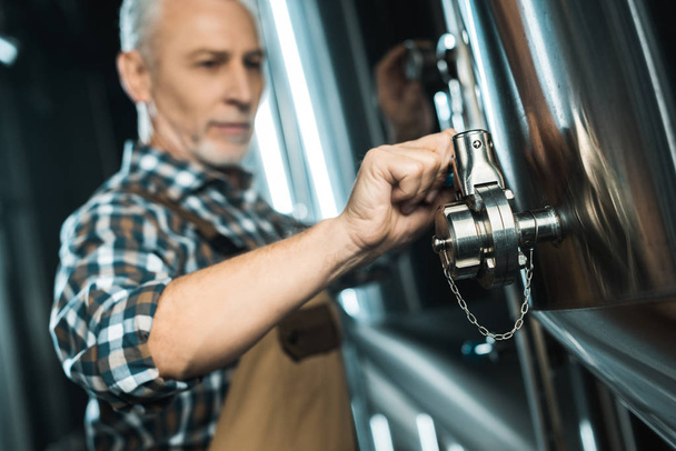 シニア男性ビール醸造所装置の操作の選択と集中 - 写真・画像