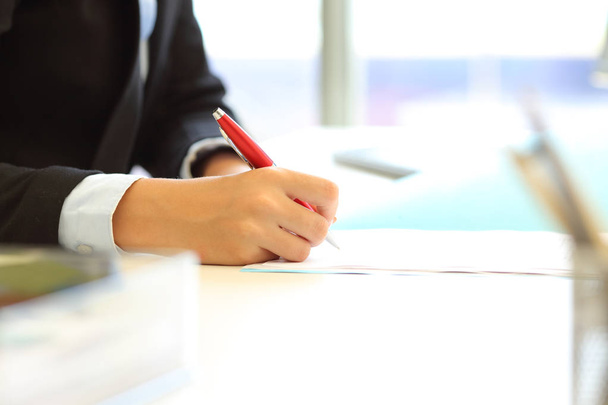 Close up van een kantoor werknemer hand contract tekenen of schrijven op document op een desktop - Foto, afbeelding