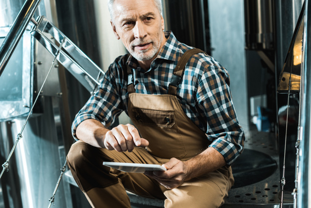 mannelijke senior brouwer met behulp van digitale tablet in brouwerij - Foto, afbeelding
