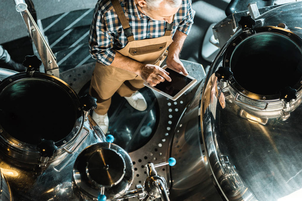 вид сверху на мужской пивовар с помощью цифрового планшета и работы на пивоварне
 - Фото, изображение