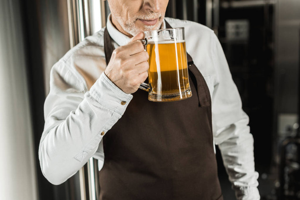 vista recortada del propietario senior probando cerveza en cervecería
 - Foto, Imagen