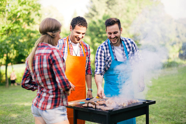 Happy friends enjoying barbecue party outdoors - Fotó, kép