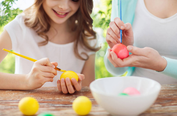 happy smiling girl and mother coloring easter eggs - 写真・画像