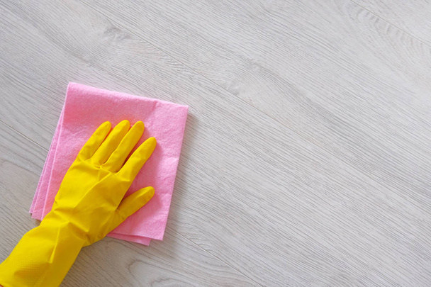 オフィス、自宅の概念をクリーニングします。マイクロ繊維の布と黄色のゴム製保護手袋の手は、木の床を掃除します。コピー スペース. - 写真・画像