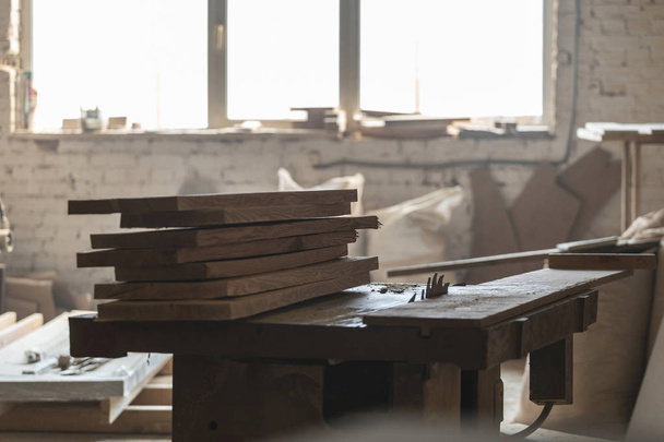 Design-Holzkonzept. altmodische rostige Zimmermannswerkzeuge, die unter hölzernen Fliesenplatten liegen. Foto von Holzdielen auf Sägetisch in leeren Garagen oder Werkräumen - Foto, Bild