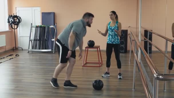 Overweight male and female trainer with perfect body burn calories by workout. Personal training from athletic girl for fatboy with big abdomen in sportswear. Fat man training with woman instructor - Imágenes, Vídeo