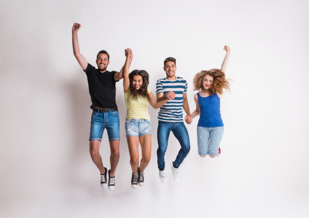 Retrato de un alegre grupo de amigos saltando en un estudio
. - Foto, Imagen