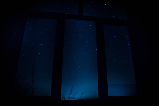 Cena noturna de estrelas vistas pela janela do quarto escuro. Céu noturno dentro do quarto escuro. Longa exposição tiro
 - Foto, Imagem