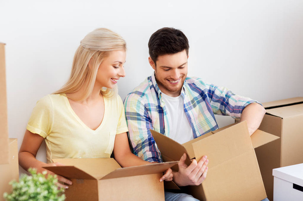 happy couple unpacking boxes at new home - Photo, Image