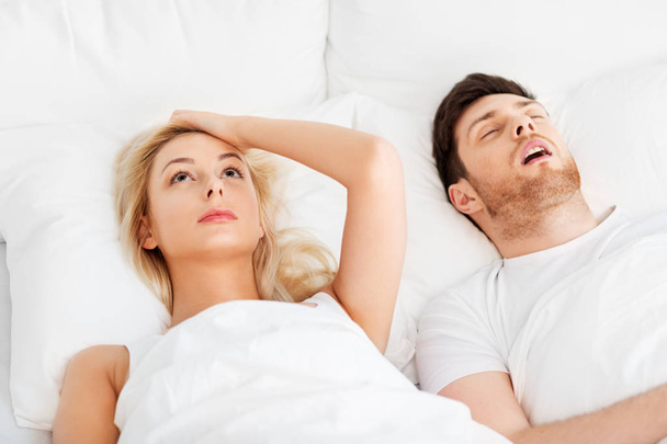 unhappy woman in bed with snoring sleeping man - Foto, Imagen