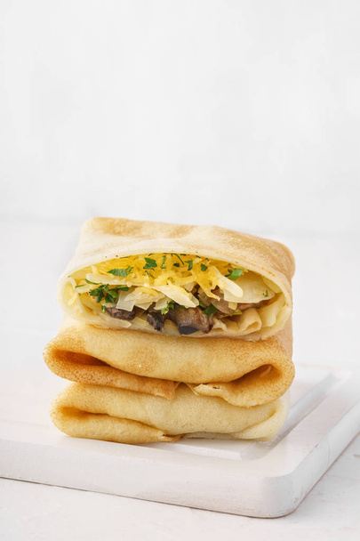 Stack of vegetarian crepes or blintzes with cabbage, mushrooms and cheese filling for breakfast. - Фото, зображення
