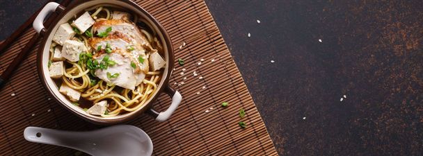 Asian miso ramen noodles with chicken and tofu. Dark background. Long banner. - Photo, image