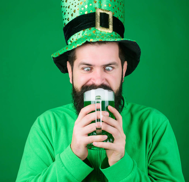 A quick death and an easy one. Hipster in leprechaun hat holding beer mug. Bearded man toasting to saint patricks day. Celebrating saint patricks day in bar. Irish man with beard drinking green beer - Φωτογραφία, εικόνα