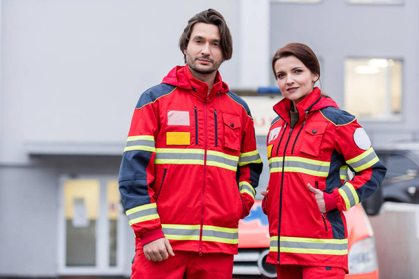 Záchranáři v červených uniformách, stojící na ulici a při pohledu na fotoaparát - Fotografie, Obrázek