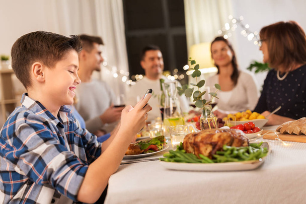 boy with smartphone at family dinner party - Foto, immagini