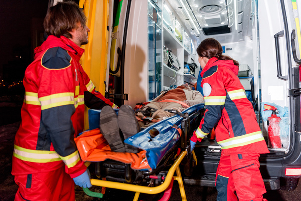 Paramedici transportating patiënt op gurney in ambulance auto - Foto, afbeelding