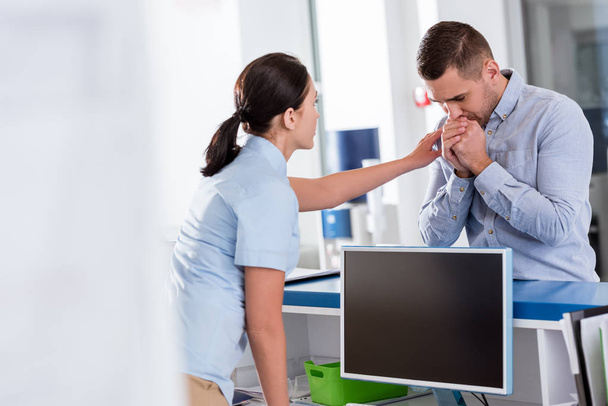 Enfermera en uniforme azul alentando molesto paciente en la clínica
 - Foto, Imagen