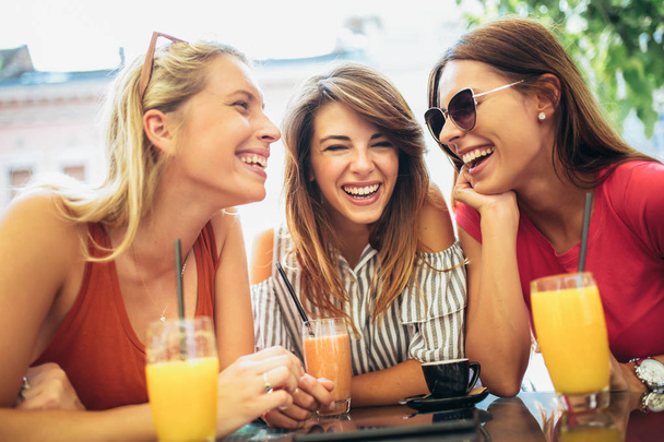 Tres hermosos amigos en un café divirtiéndose
 - Foto, Imagen
