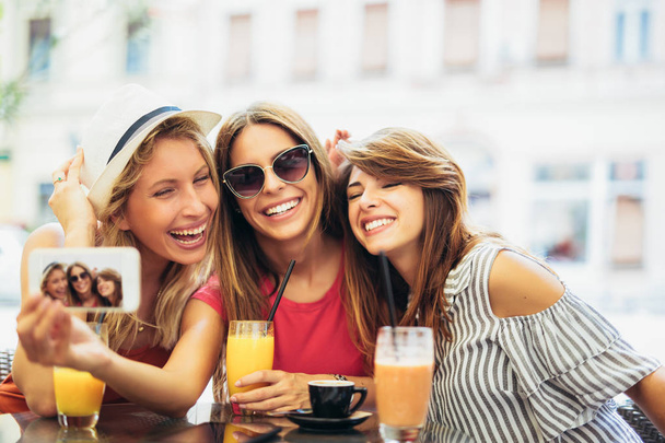 Drie jonge vrouwen in een café na een winkelen maken selfie foto - Foto, afbeelding