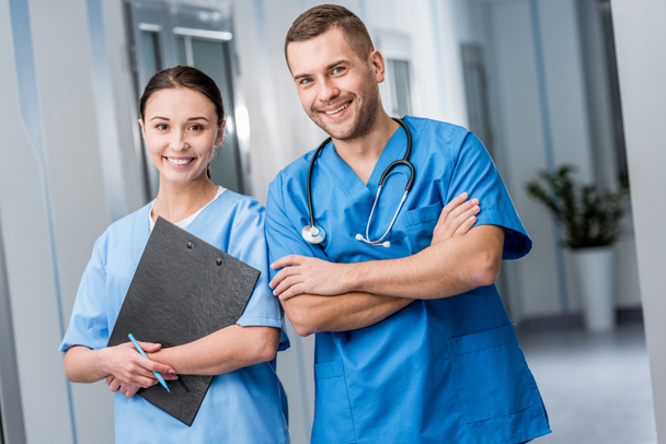 Médicos sonrientes en uniforme azul sosteniendo estetoscopio y portapapeles
 - Foto, Imagen