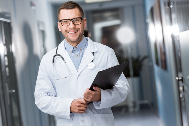 Smiling doctor in glasses holding black folder - Photo, Image