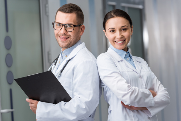 Smiling doctors with clipboard looking at camera - Photo, image