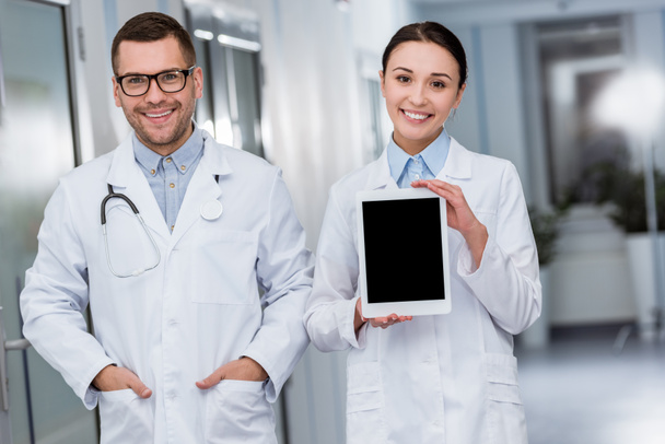 Smiling doctors with digital tablet looking at camera - 写真・画像