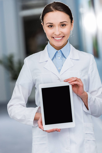 Riendo doctora en bata blanca sosteniendo tableta digital con pantalla en blanco
 - Foto, Imagen
