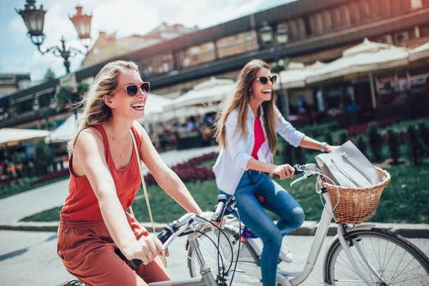 Дві красиві жінки купують на велосипеді в місті
 - Фото, зображення