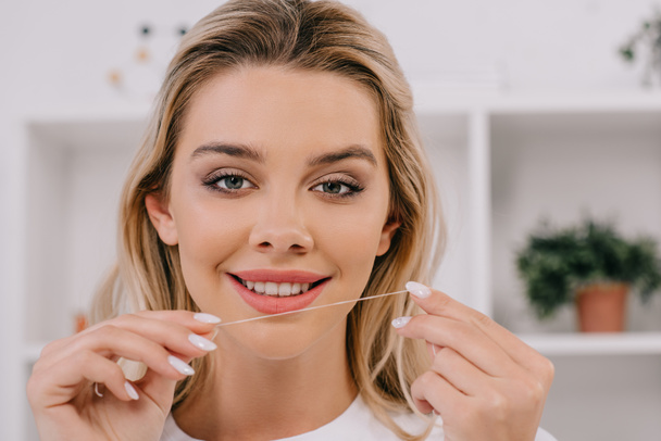 beautiful smiling woman holding dental floss and looking at camera - 写真・画像